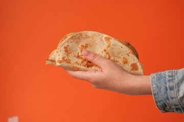 Mexican national food taco or Tatar national food kystyby in hand on an orange background.Food in a tortilla.National food concept