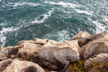 Top view photo of  Atlantic ocean waves hitting rocks on the beach with turquoise sea water. Amazing rock cliff seascape in the Portuguese coastline. Peniche costline.