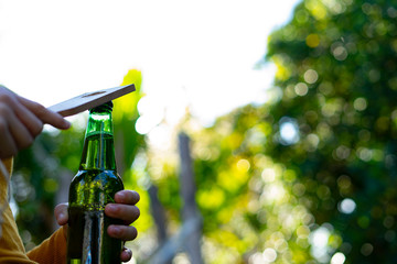 Opening a beer bottle with a bottle opener.