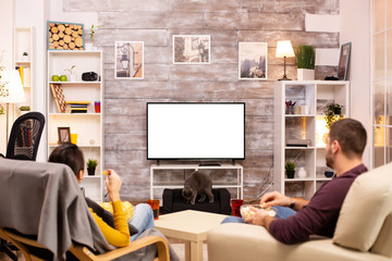 Couple looking at isolated TV screen in cozy living room