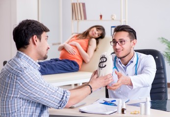 Obraz premium Pregnant woman with her husband visiting the doctor in clinic