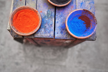 Travel by Morocco. Plates with natural colorful paint powder on wooden table.
