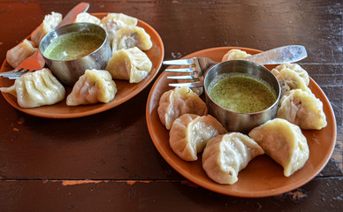 Indian kitchen. Tasty chicken momos with spicy kenza sauce on a wooden vintage background.