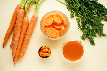 Flat lay composition with fresh carrot juice and ripe carrots on a yellow background.