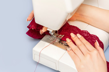 Female hand sewing on a sewing machine. Work with lace. Close-up.