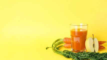 Fresh carrot juice and ripe carrots & apple on a yellow background, with space for text.
