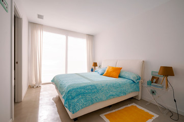 Fototapeta na wymiar Modern bedroom in green overlooking the sea. Blue and yellow pillows, carpet and blanket.