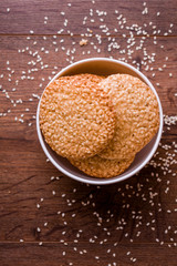 Round sesame cookies with milk and juice on the table.
