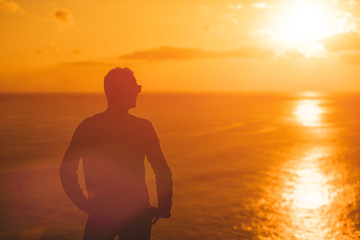 Man with nice tropical summertime sunset on the island above the ocean.