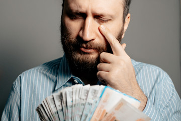 Russian ruble falling down inflation concept. Portrait of man looks at money rubles holding his...
