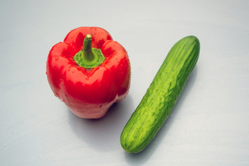 Red juicy peppers and green cucumber on a gray background