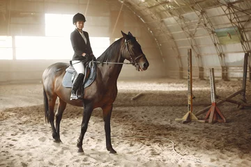 Foto auf Acrylglas Woman on a horseback. Rider in a black uniform © prostooleh
