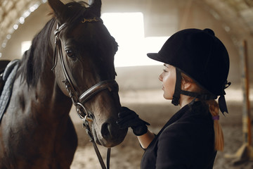 Woman near horse. Rider in a black uniform
