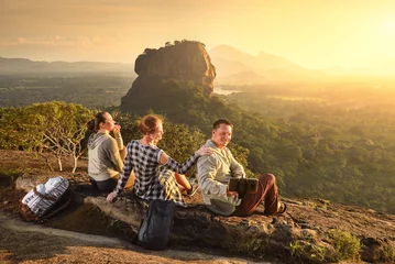 Foto op Aluminium Group young tourists relaxes and watches during vacation colorful sunset on background of famous rocky plateau Lion peak, Sigiriya. Sri Lanka © soft_light