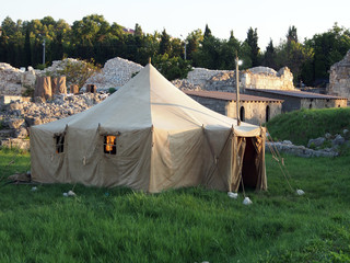 The tent stands on the site of archaeological excavations, against the background of the...