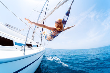 Young woman enjoys tropical sailing in the hammock set on the yacht