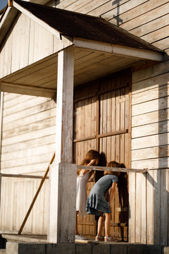 Girls Peep And Stand Against  Wooden Door 