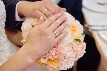 Obraz na płótnie Canvas Newlywed hands with wedding rings on bridal bouquet, copy space. Wedding couple, bride and groom, hands with rings, closeup
