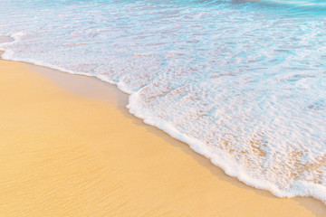 Fototapeta na wymiar Tropical shore. Sandy beach and wavy sea in warm sunset light.