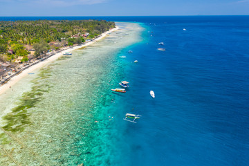 Aerial drone view of snorkelers and boats above a coral reef in a clear, tropical ocean