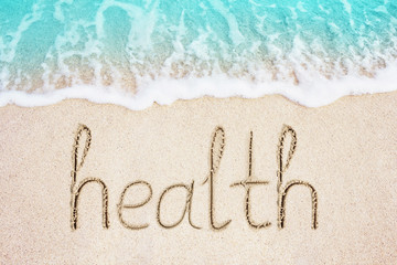 Health word written in the sand, beach with blue sea wave background