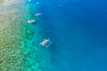 Aerial drone view of snorkelers and boats above a coral reef in a clear, tropical ocean