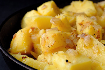 Freshly fried potatoes with onions in a pan closeup. Shallow depth of field
