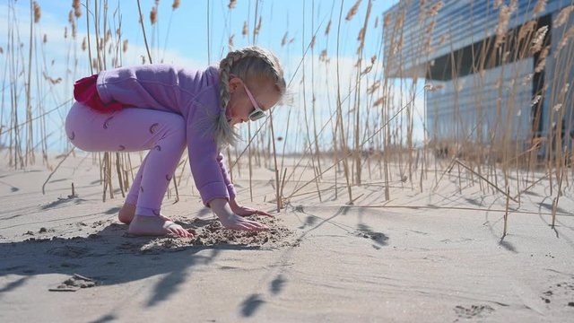 little girl playing in sand on beach along Lake Michigan near Chicago in Spring