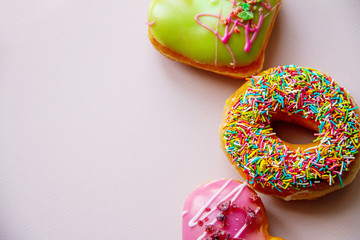 Top view of assorted donuts on pink concrete background with copy space. Colorful donuts background.