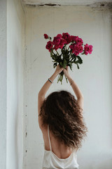 Girl in silk top with bunch of peonies, back view - 329297659