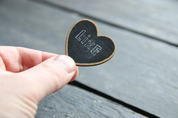 like idea, hand holds a sign in the form of a heart with the inscription