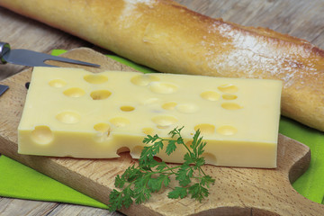 tranche d'emmental et baguette de pain sur une table