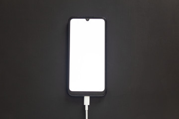 The phone on a black background with a luminous screen is charging.