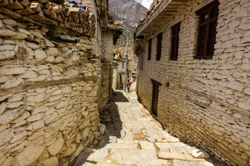 The narrow lanes between old, traditional, white wood and stone houses in the village of Chairo on the Annapurna Circuit trail in the Nepal Himalaya.
