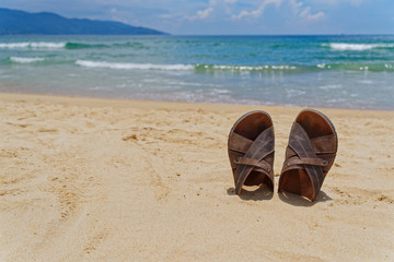 Sandal shoes in a sand on the seashore against horizon and sky