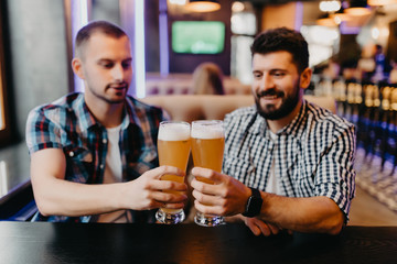 Two mens drinking beer in bar, clinking beer have fun in pub