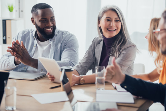selective focus of smiling multicultural businesspeople talking with their colleagues