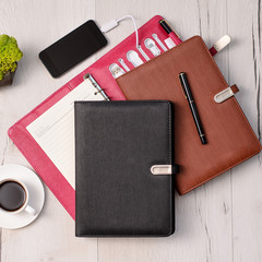 Three leather notebooks with built in power bank on wooden background with green fresh moss and cup of coffee. Set of diary or notebook in hard leather cover on wood table. Copy space..