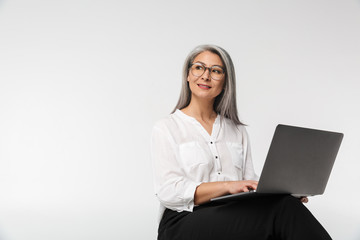 Image of adult mature woman wearing office clothes using laptop computer