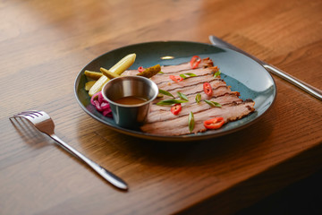 Carpaccio of beef with red cabagge and pickles served on blue plate on rustic wooden table in a...