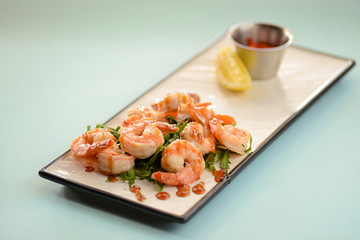Shrimp or prawn salad, with arugula and a healthy lemon and parsley dressing served on a white plate