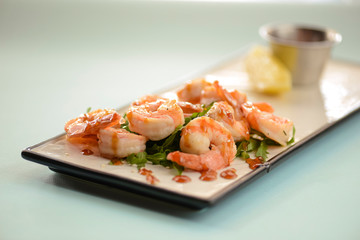 Shrimp or prawn salad, with arugula and a healthy lemon and parsley dressing served on a white plate