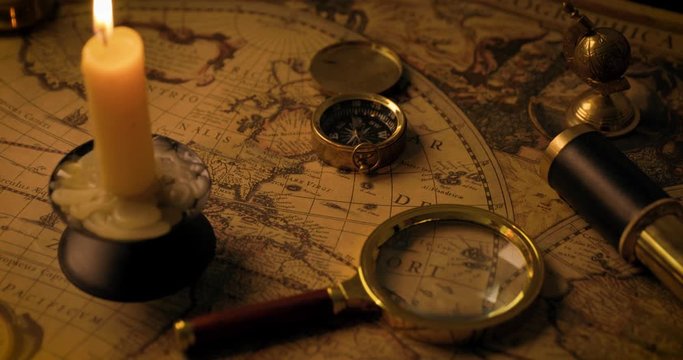 exploration concept - antique objects on old world map in candlelight. dolly shot