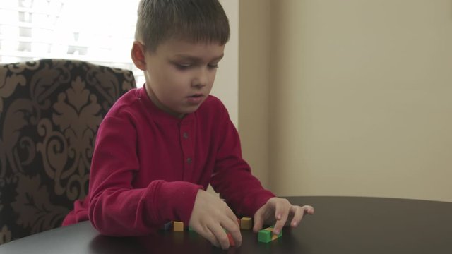 Small child, preschooler playing with wooden blocks. Caucasian boy in a red sweater building with blocks.