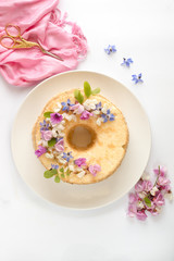Angel cake su piatto bianco, decorata con fiori e sfondo bianco
