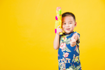 little children boy so happy in Songkran festival day holding water gun