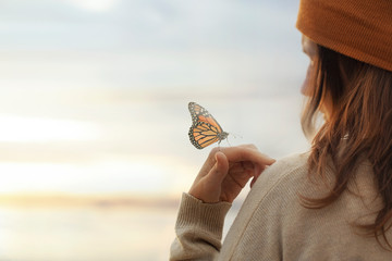 colorful butterfly is laying on a woman's hand - obrazy, fototapety, plakaty