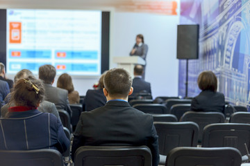 the young man listens attentively to the lecturer at the conference. Back view