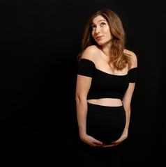 Fototapeta premium Studio shoot of happy emotional pregnant woman on black background
