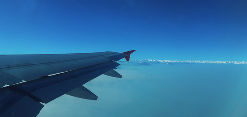 wing of airplane flying above clouds